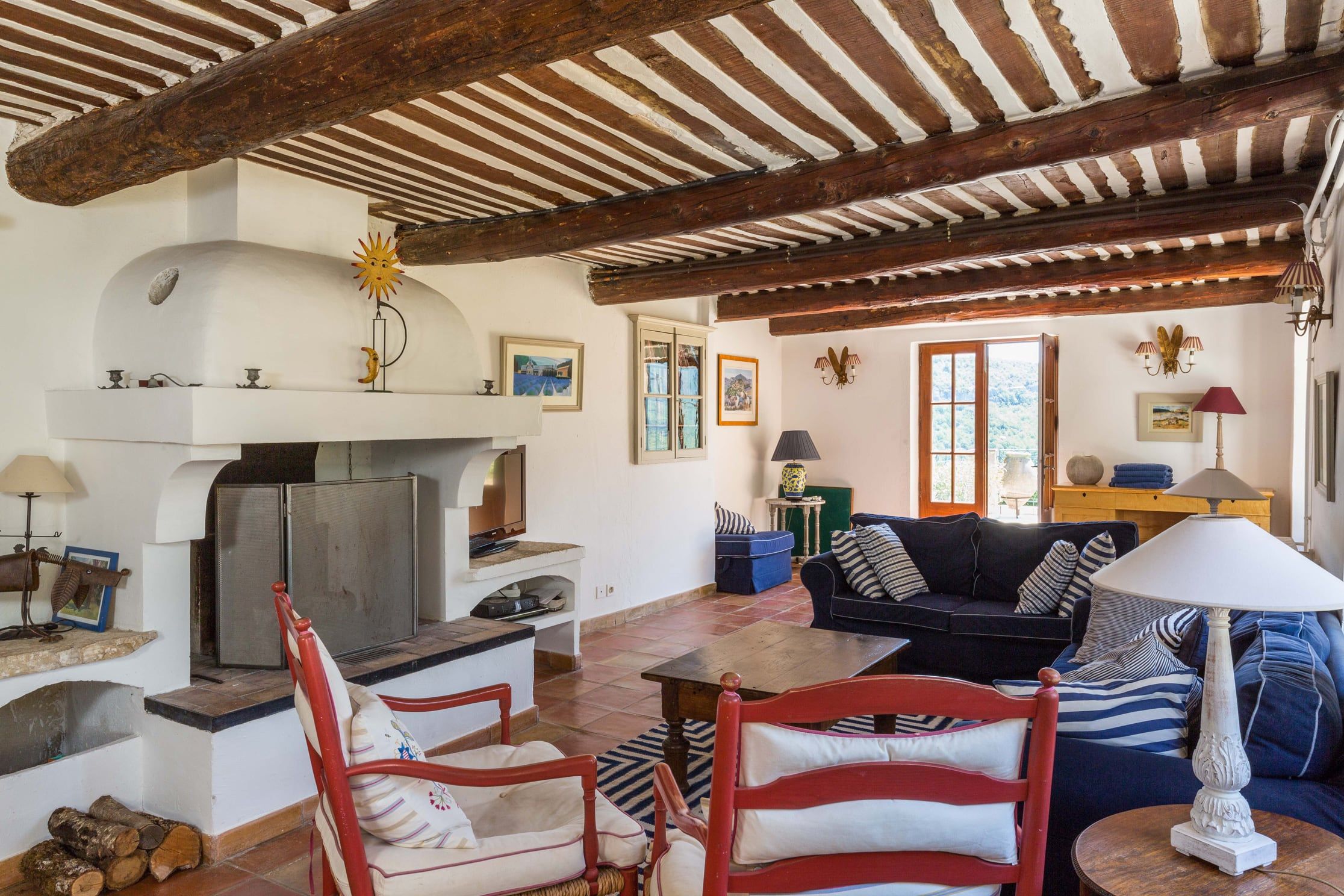 Living room with a beamed Provençal ceiling, a large fireplace and sofas