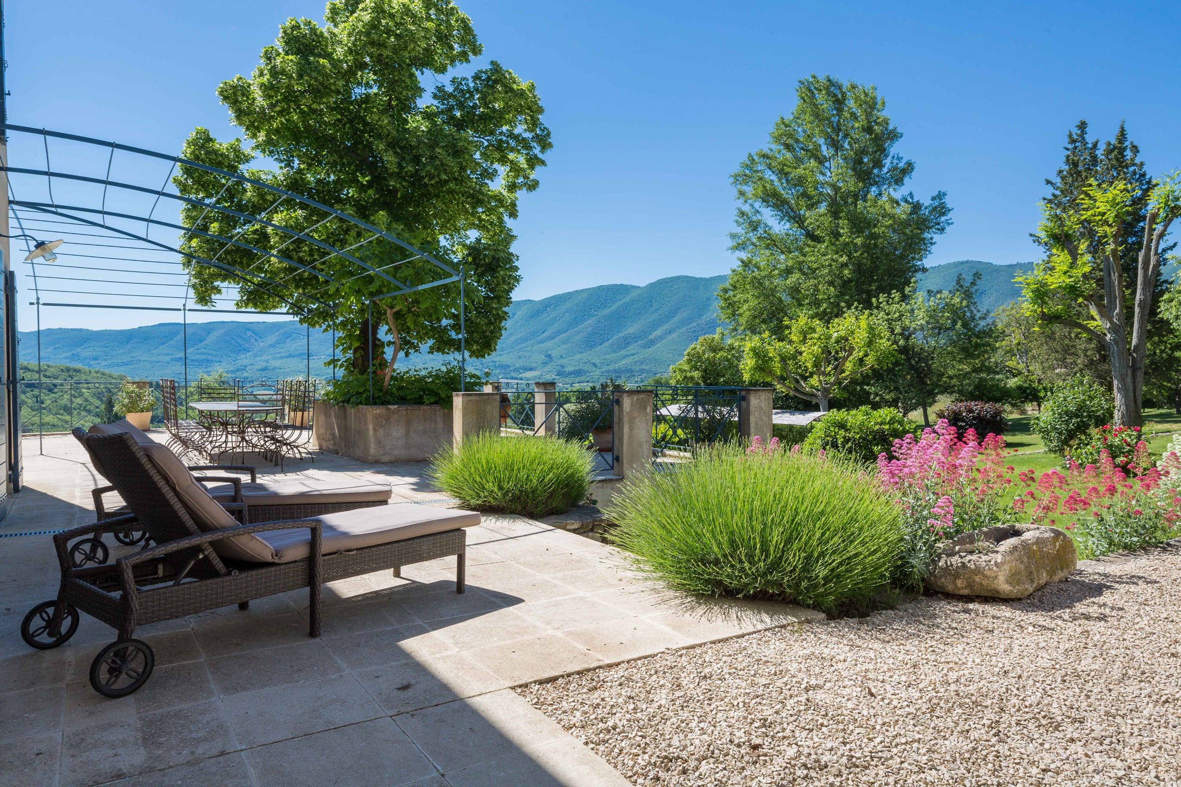 Sun lounger on the terrace under the pergola, with lavender and the Luberon hills beyond